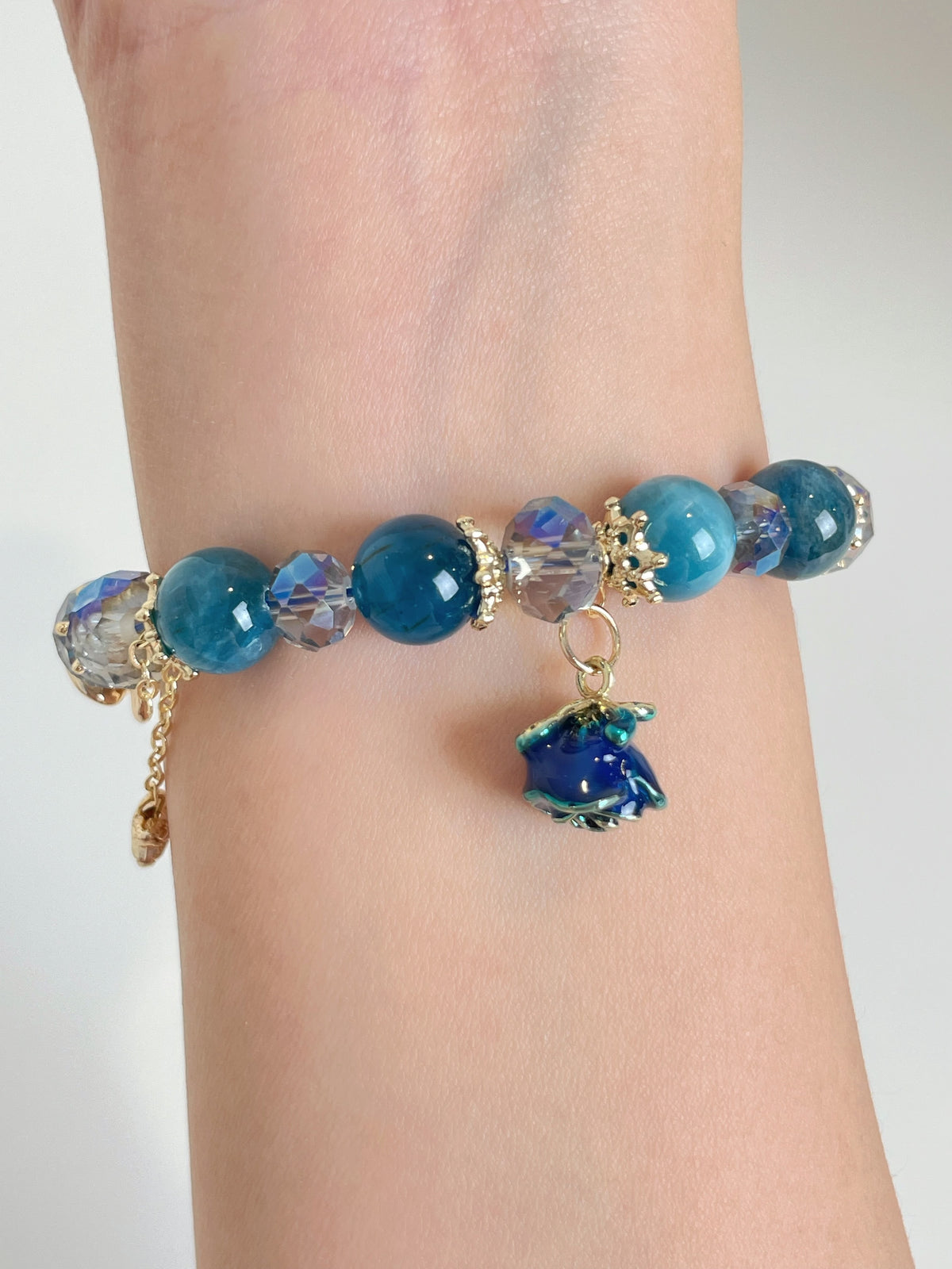 A beautiful blue apatite bracelet featuring 10mm beads, accented with sparkling crystals and a charming flower charm.