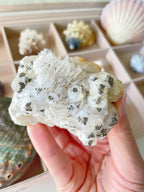 Beautiful pyrite on pagoda calcite specimen held in hand, showcasing intricate textures and natural formations.