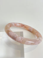 Beautiful flower agate bangle with soft pink hues, displayed on a clear stand, showcasing its smooth finish.