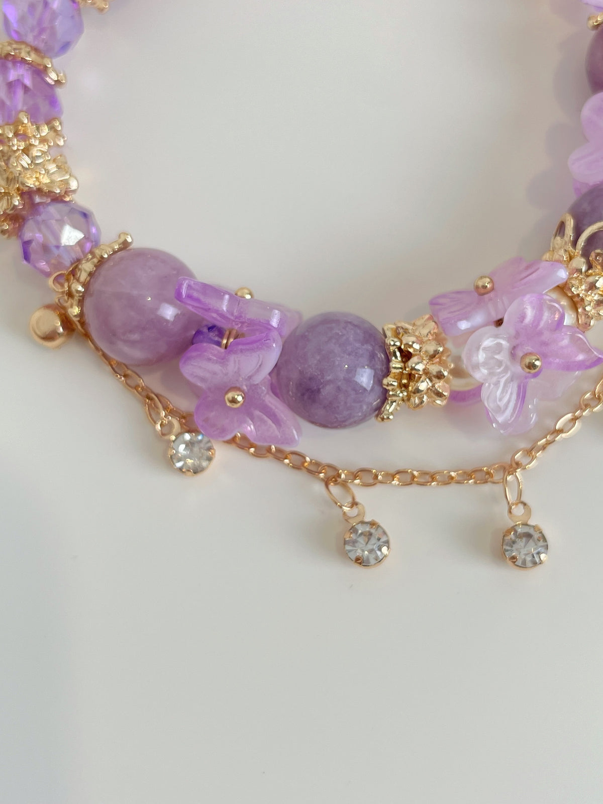 Beautiful Lepidolite butterfly bracelet featuring purple beads and floral accents, accented with gold details.