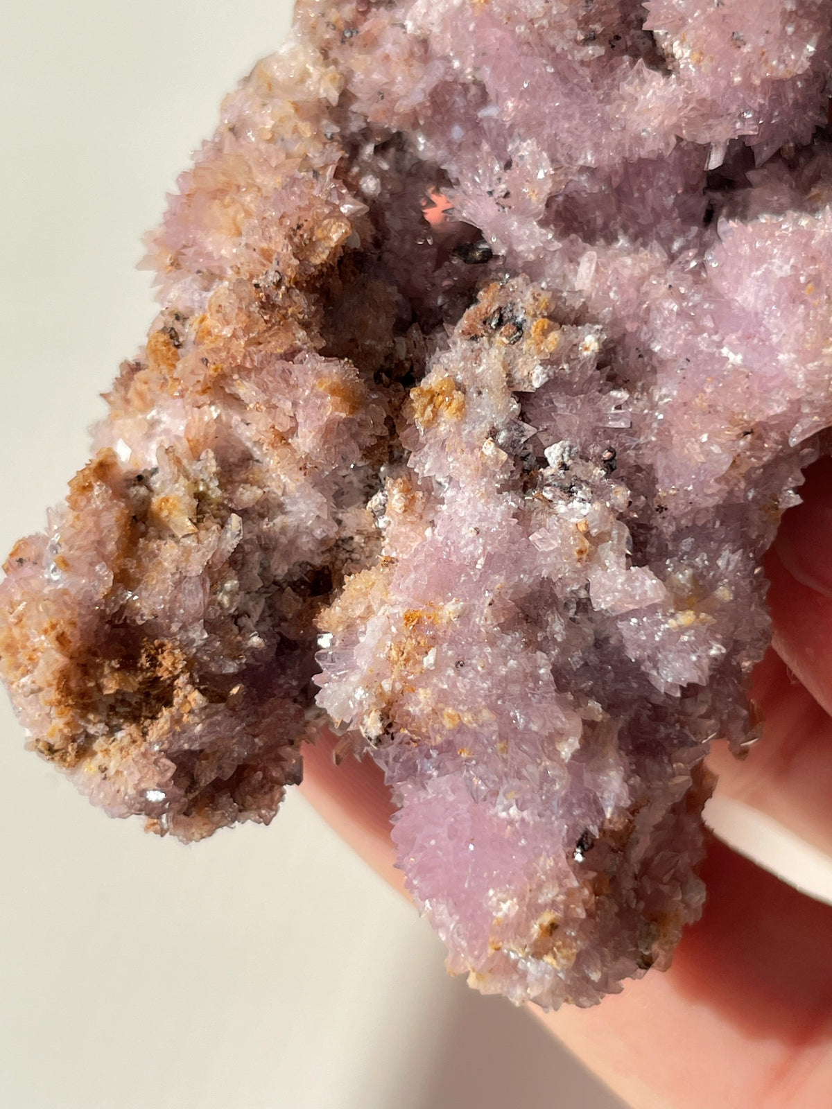 Beautiful purple creedite specimen with sparkling crystals, held in a hand, showcasing its natural texture.