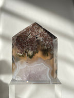 Scenic moss agate crystal tower with earthy tones and unique patterns, displayed on a clear stand.