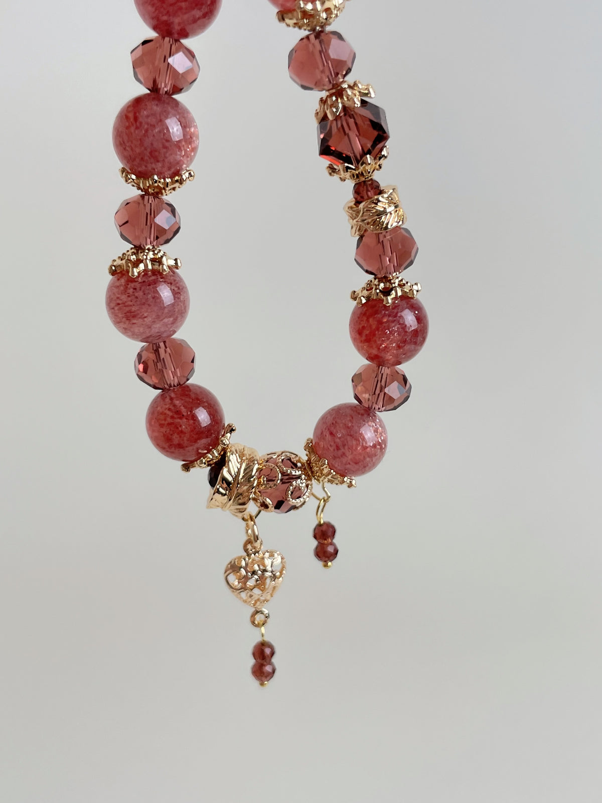 Beautiful strawberry quartz bracelet featuring 10mm beads, accented with gold and sparkling crystals.
