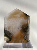Scenic moss agate tower with earthy tones and intricate patterns, displayed on a clear base.