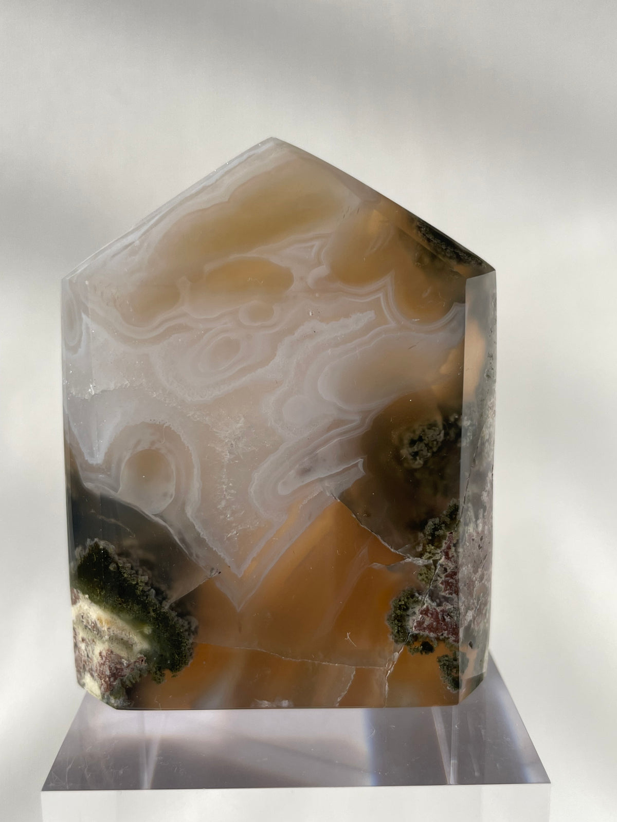Scenic moss agate tower with earthy tones and intricate patterns, displayed on a clear base.