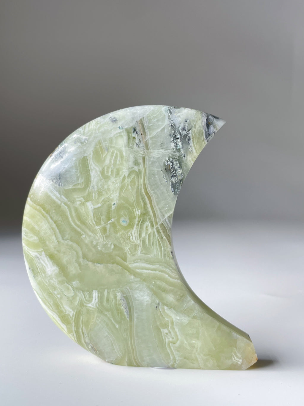 Green Maligano Jasper moon-shaped crystal specimen with unique patterns and textures, beautifully displayed.