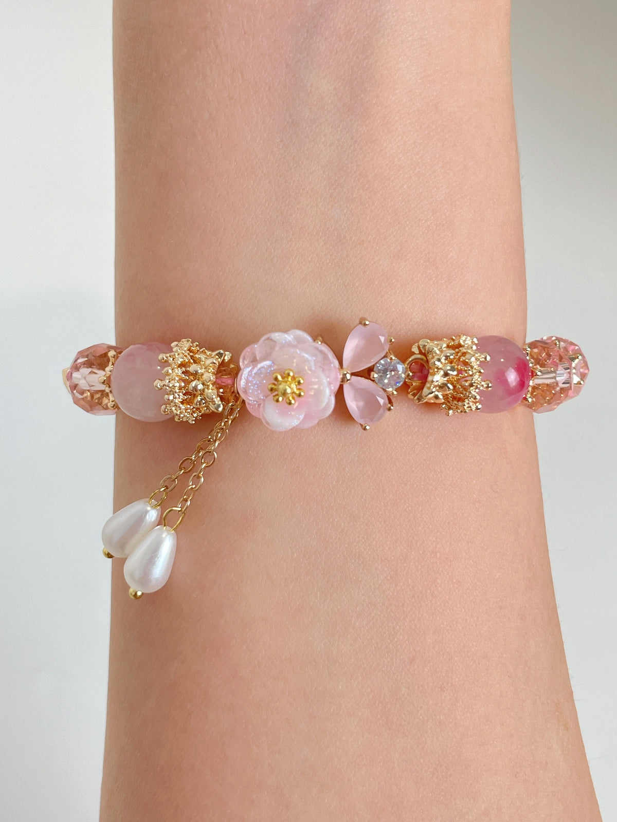 Beautiful Sakura Agate bracelet featuring pink and floral accents, adorned with gold details and pearl charms.