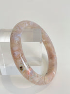 Beautiful flower agate bangle with soft pink hues, displayed on a clear acrylic stand.