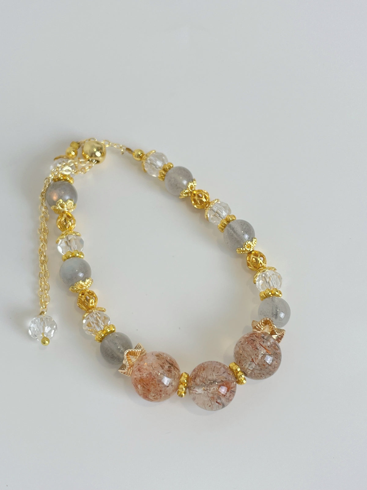 Beautiful rutilated quartz bracelet featuring 7-10mm beads with gold accents and a secure clasp.