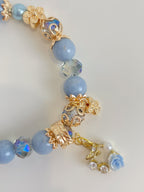Beautiful Angelite bracelet featuring 8.5mm light blue beads, gold accents, and charming floral details.