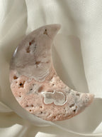 Beautiful flower agate moon with soft pink and white patterns, resting on a light fabric background.