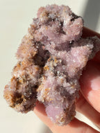 Beautiful purple creedite crystal specimen with sparkling texture, held in a hand, showcasing its unique formation.