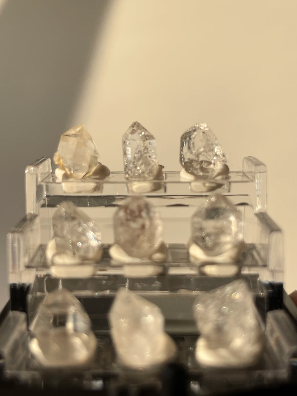 Nine mini Herkimer diamonds displayed in a clear box, showcasing their unique crystal formations and clarity.