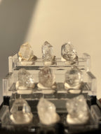 Nine mini Herkimer diamonds displayed in a clear box, showcasing their unique crystal formations and clarity.