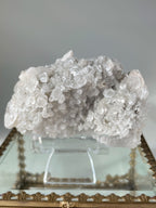 Beautiful crystal specimen featuring pyrite and calcite on quartz, displayed on a decorative stand.