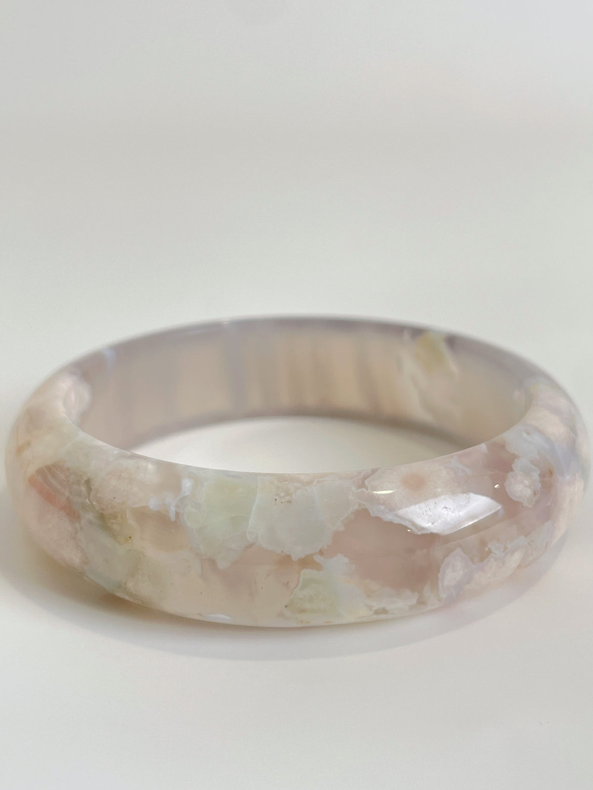 Beautiful flower agate bangle showcasing soft pink and cream hues with a smooth, glossy finish.