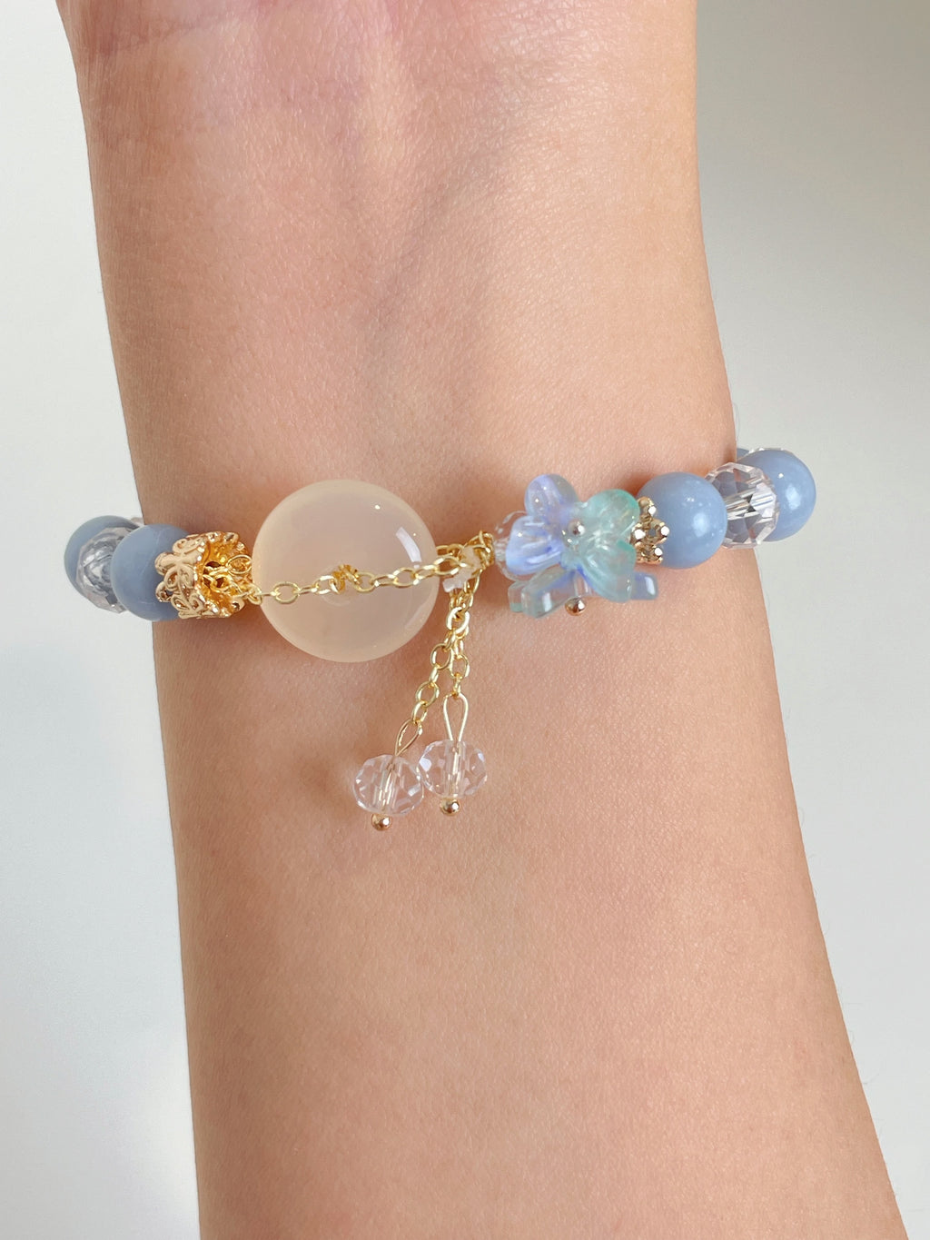 Beautiful Angelite donut bracelet featuring soft blue beads and delicate floral accents, elegantly worn on a wrist.