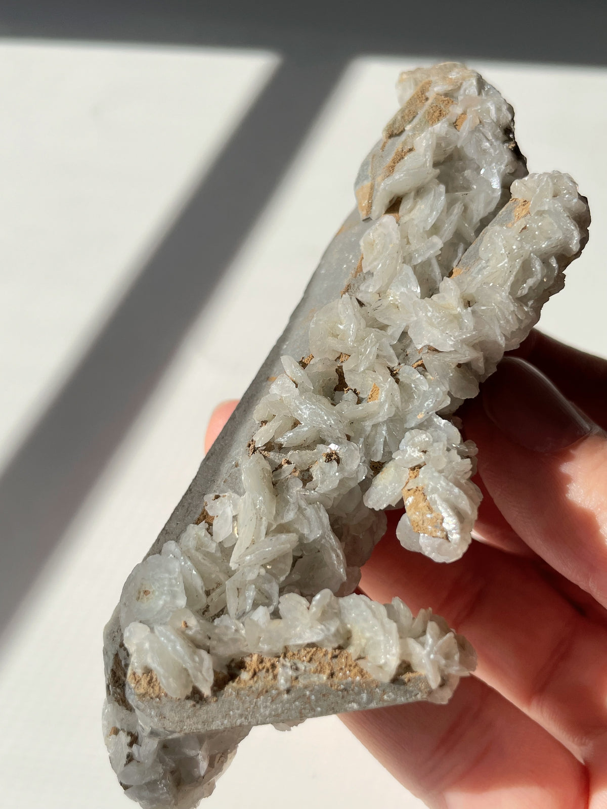 Beautiful crystal specimen featuring flower calcite on chlorite-included quartz, held in hand with natural light.