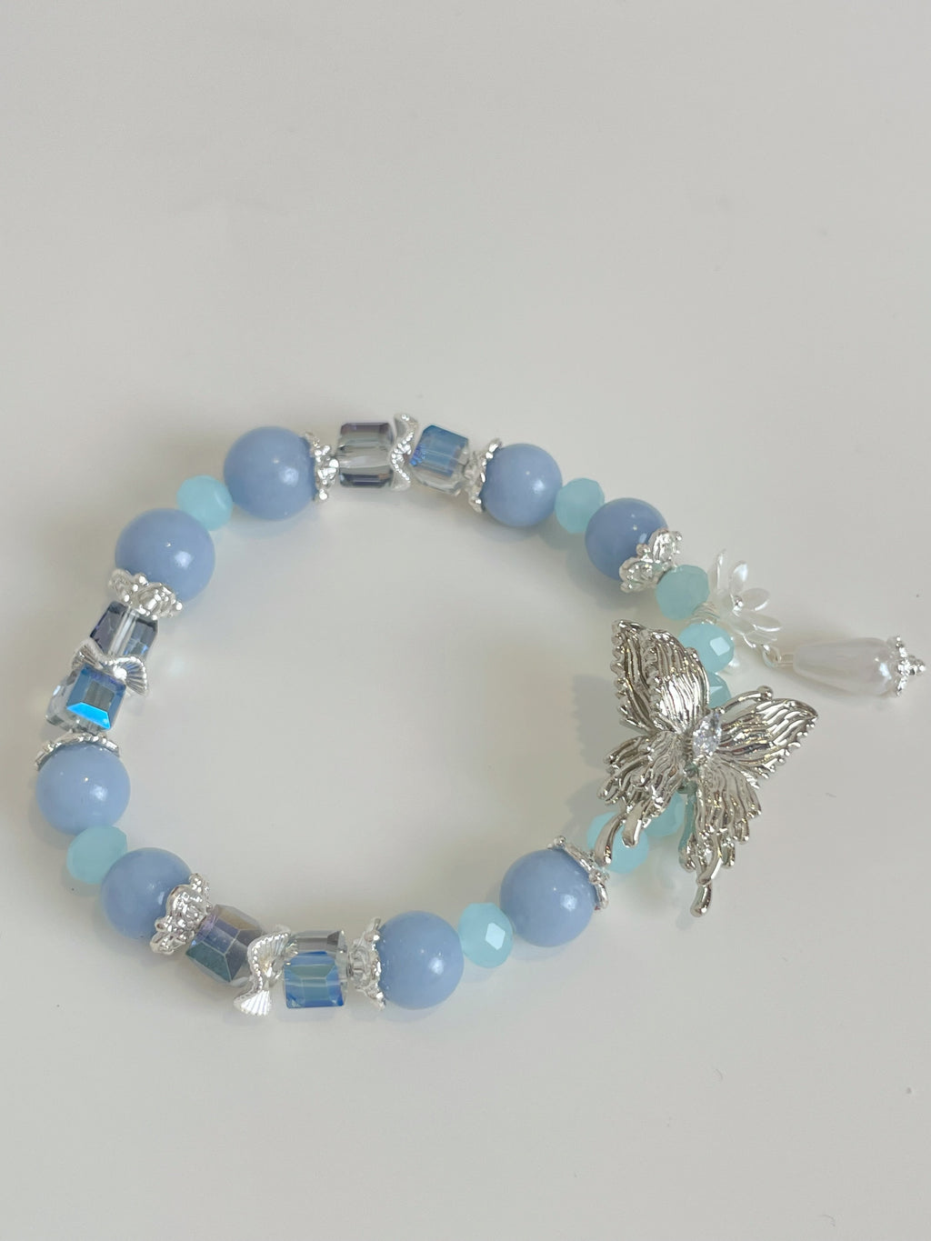Beautiful bracelet featuring light blue beads, silver butterfly charm, and decorative accents.
