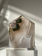 Scenic moss agate crystal tower with earthy tones and natural patterns, beautifully displayed on a clear base.