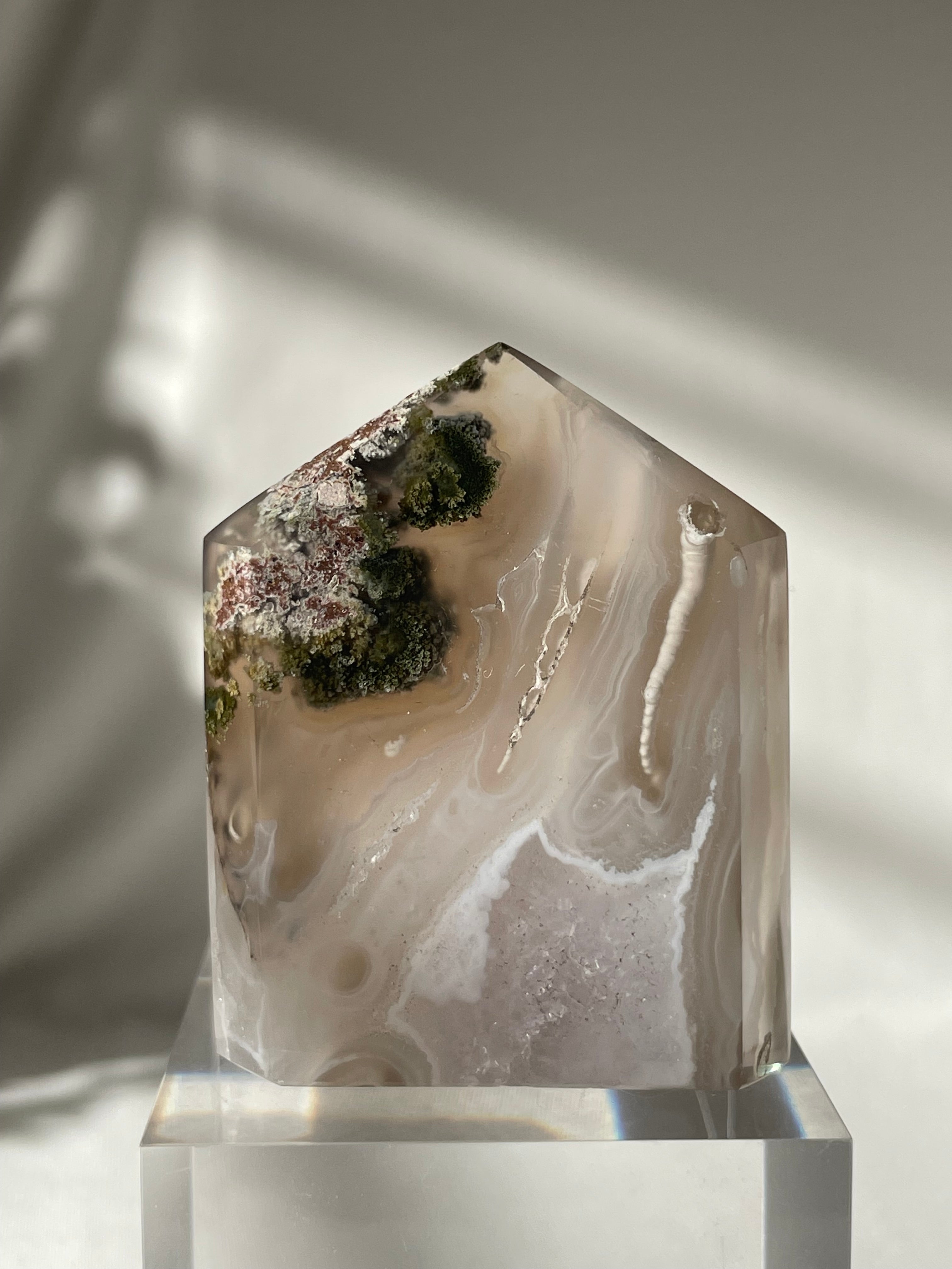 Scenic moss agate crystal tower with earthy tones and natural patterns, beautifully displayed on a clear base.