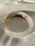 Beautiful flower agate bangle showcasing soft pink and earthy tones, resting on a light fabric background.