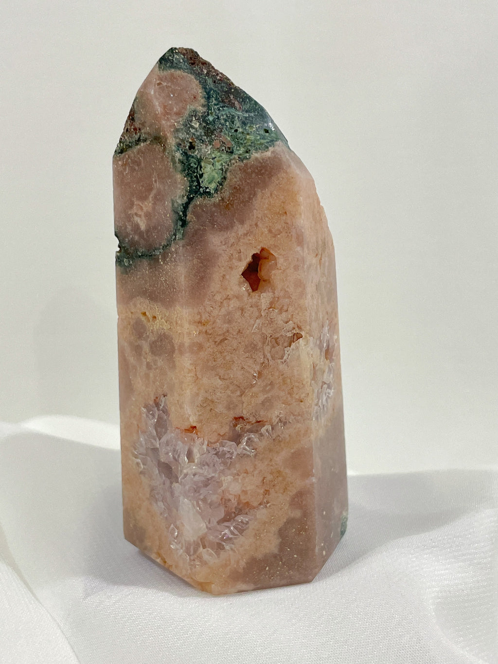 Beautiful pink amethyst tower with unique patterns and a smooth finish, resting on soft fabric.