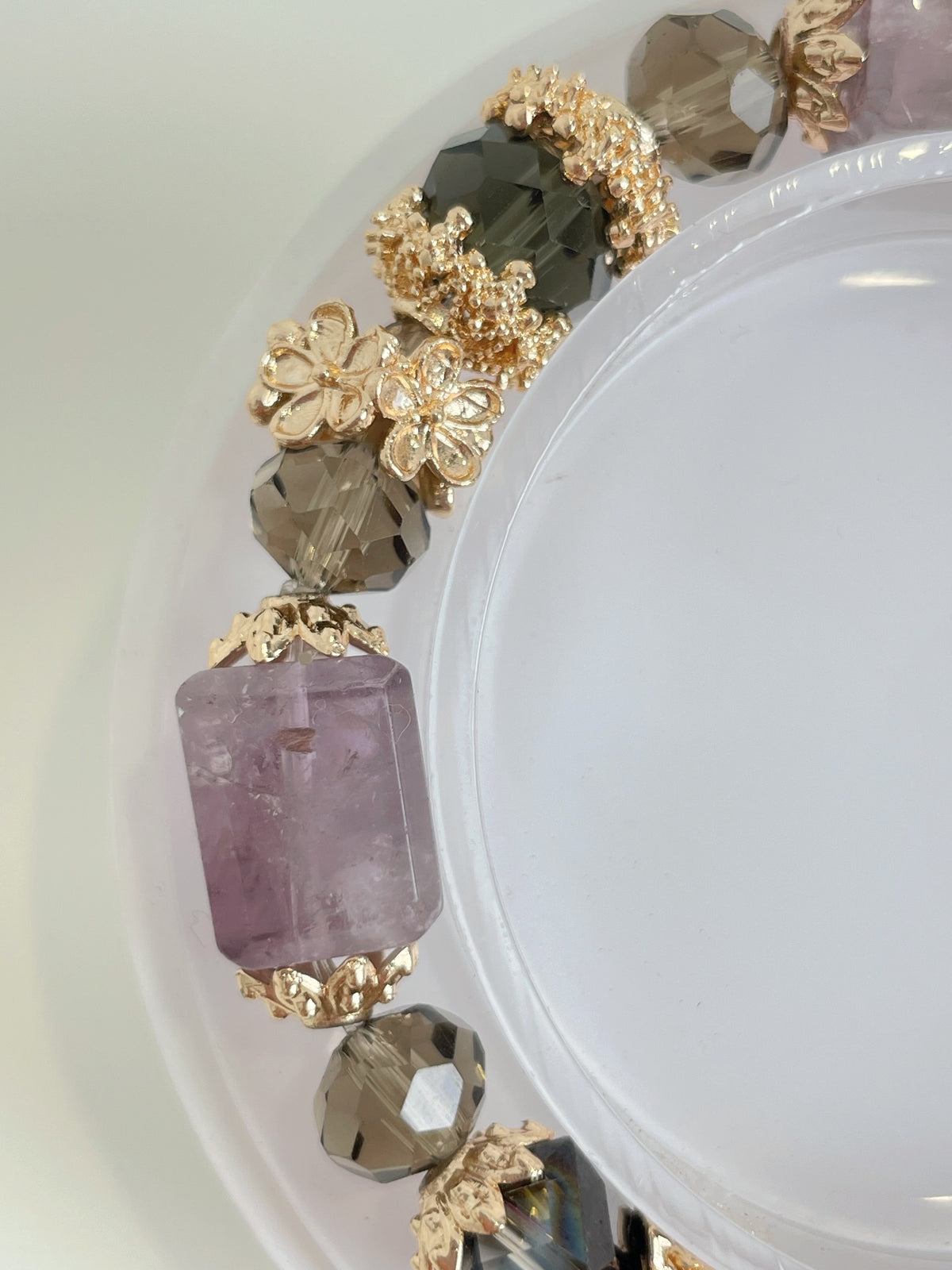 Elegant bracelet featuring a pink amethyst cube and sparkling crystal accents, beautifully arranged with floral details.