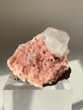 Beautiful pink Heulandite and Apophyllite crystal specimen displayed on a clear stand, showcasing its natural beauty.