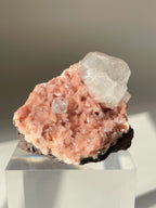 Beautiful pink Heulandite and Apophyllite crystal specimen displayed on a clear stand, showcasing its natural beauty.