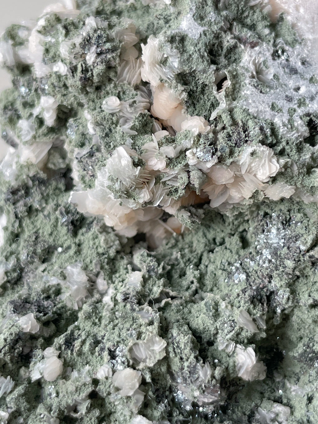A close-up view of green mineral clusters with delicate white crystal formations, showcasing natural textures.