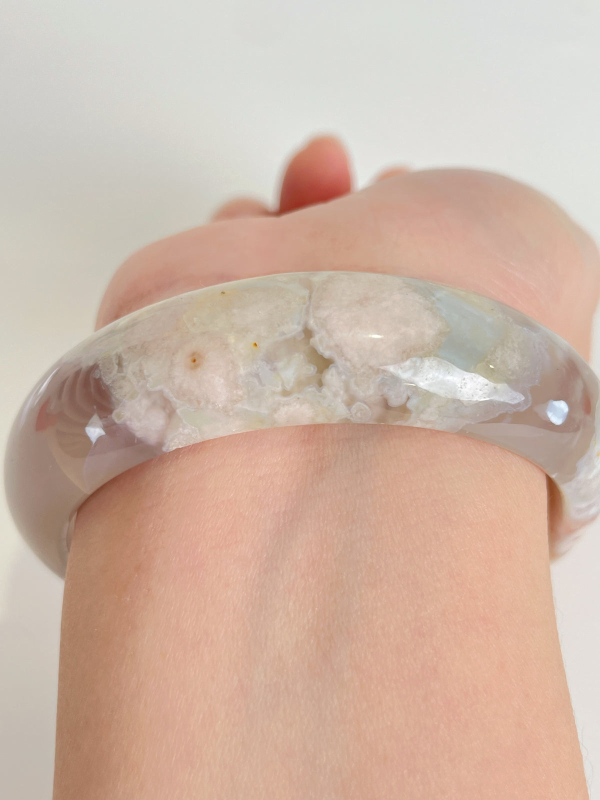 Beautiful flower agate bangle resting on a hand, showcasing its unique patterns and soft colors.