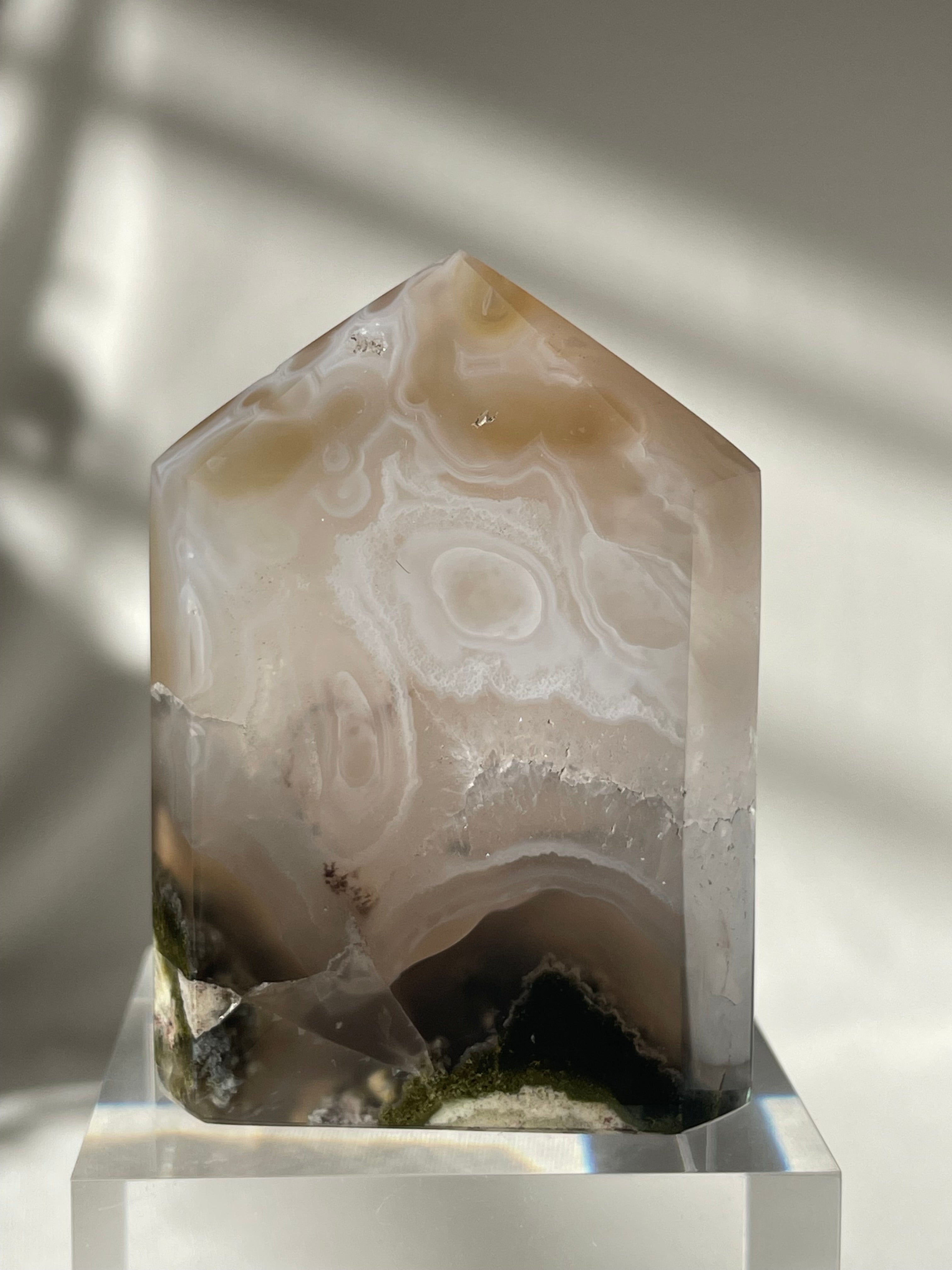 Scenic moss agate tower with unique patterns and earthy tones, resting on a clear base.