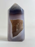 Druzy Agate Tower with smooth, layered purple and beige hues, featuring a sparkling crystal interior.