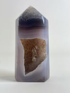 Druzy Agate Tower with smooth, layered purple and beige hues, featuring a sparkling crystal interior.
