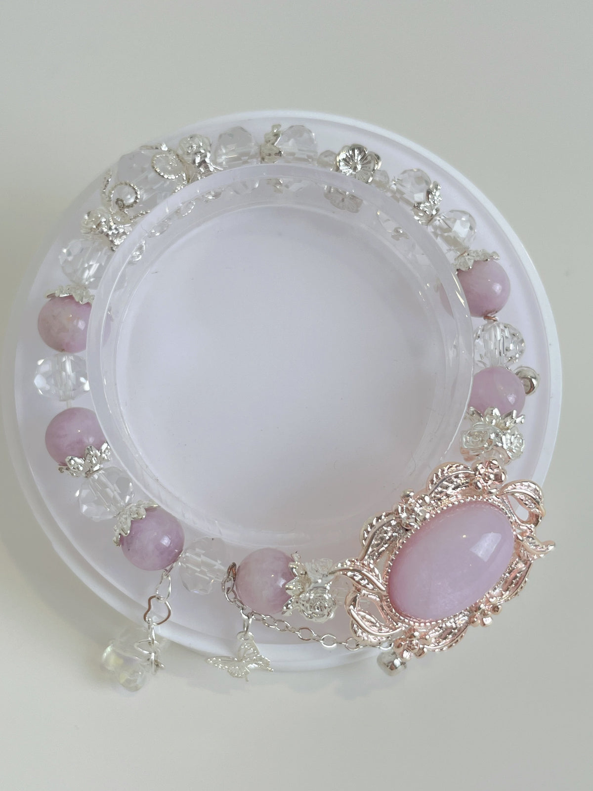 Beautiful Kunzite bracelet featuring 8mm pink stones and decorative silver accents, displayed on a clear stand.