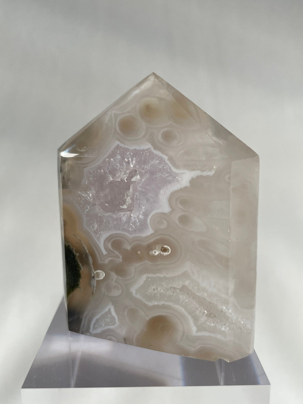 Scenic moss agate crystal tower with soft colors and unique patterns, displayed on a clear stand.