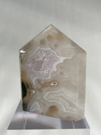Scenic moss agate crystal tower with soft colors and unique patterns, displayed on a clear stand.