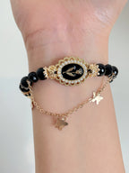 Elegant black obsidian bracelet featuring a decorative centerpiece and delicate butterfly charms.