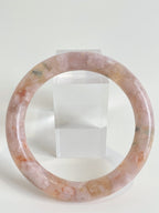 Beautiful flower agate bangle showcasing soft pink hues and natural patterns, displayed beside a clear stand.