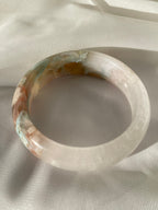 Beautiful flower agate bangle showcasing soft pink and earthy tones, resting on a light fabric background.