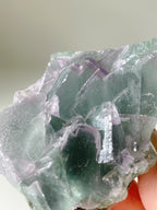 Beautiful fluorite crystal specimen showcasing vibrant green and purple hues with a textured surface.