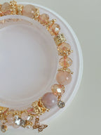 A delicate butterfly bracelet featuring flower agate and sparkling crystal beads, elegantly displayed on a circular stand.