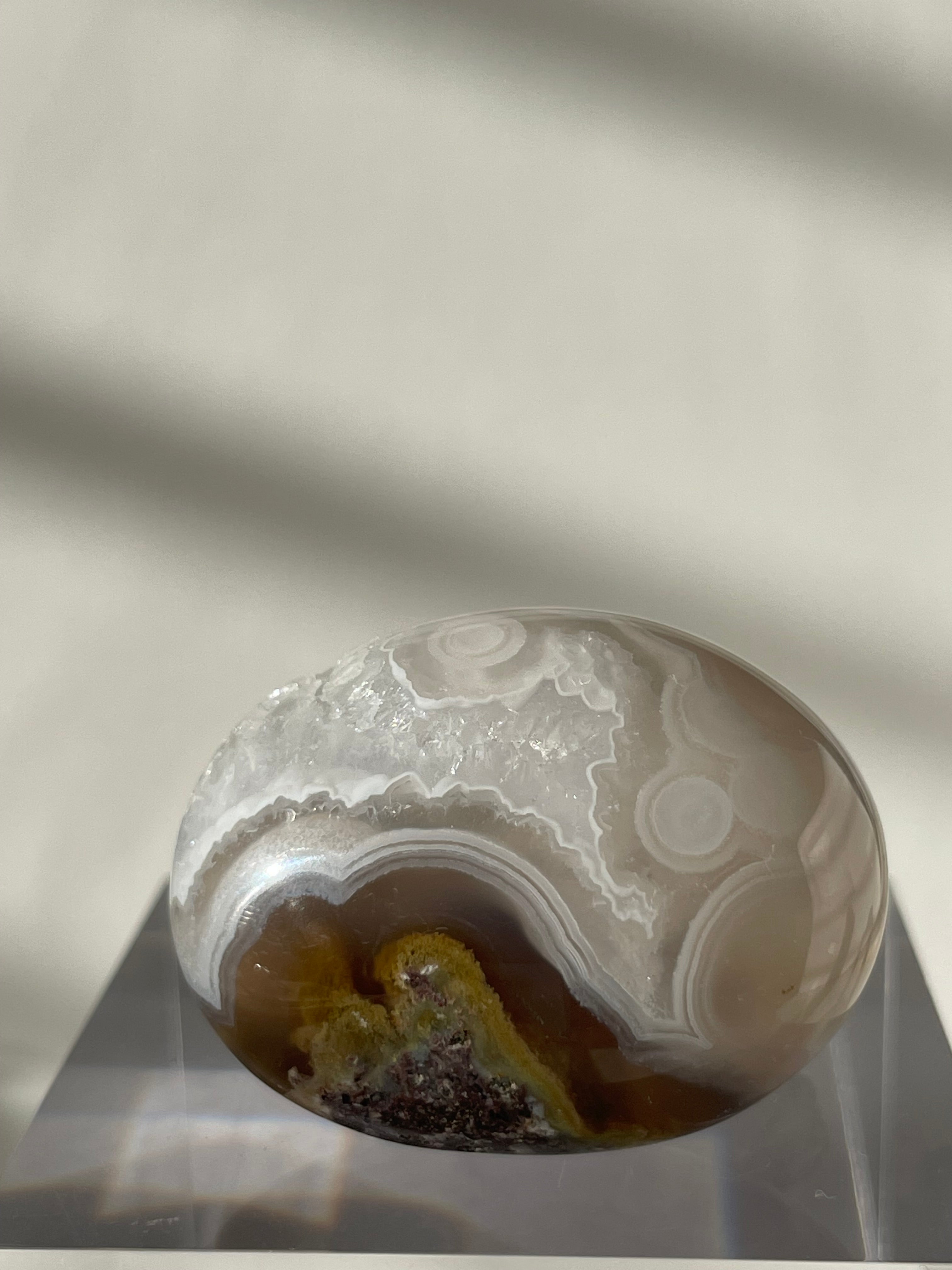 Scenic moss agate palm stone with earthy tones and intricate patterns, displayed on a clear stand.