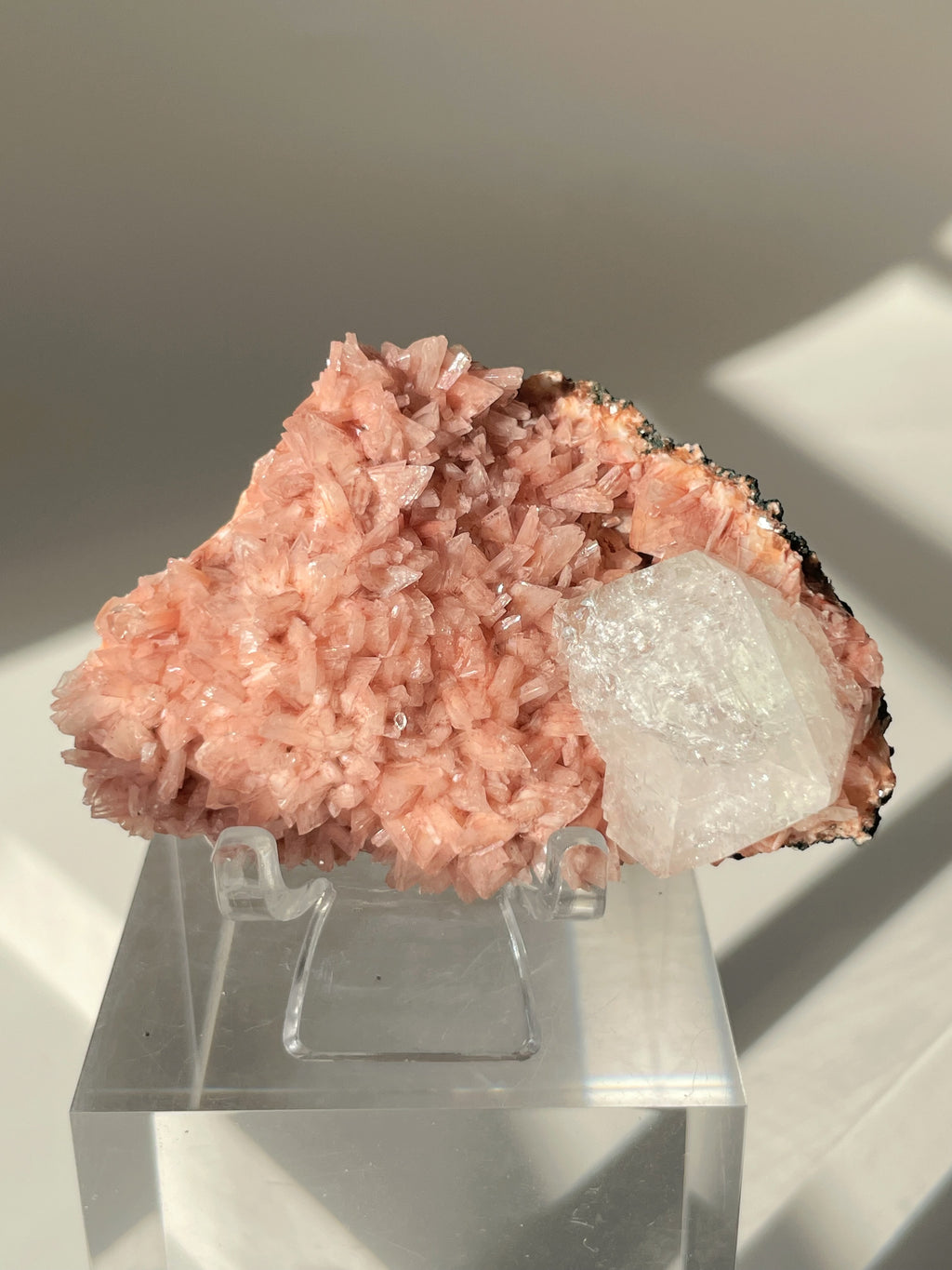 Beautiful pink Heulandite and Apophyllite crystal specimen displayed on a clear stand, showcasing its natural beauty.