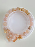 Flower agate bracelet featuring 9mm beads and a fox charm, accented with gold details, displayed on a round tray.
