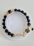 Elegant black obsidian bracelet featuring 8mm beads with gold accents and a decorative rose clasp.