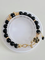 Elegant black obsidian bracelet featuring 8mm beads with gold accents and a decorative rose clasp.