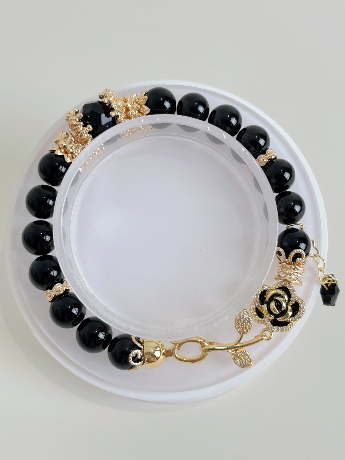 Elegant black obsidian bracelet featuring 8mm beads with gold accents and a decorative rose clasp.