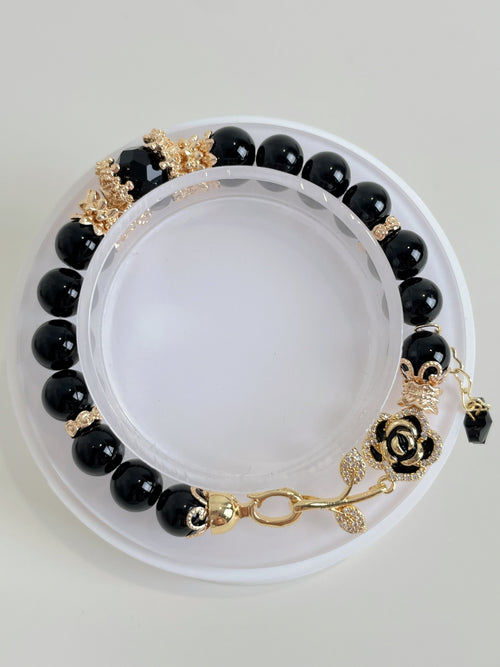 Elegant black obsidian bracelet featuring 8mm beads with gold accents and a decorative rose clasp.